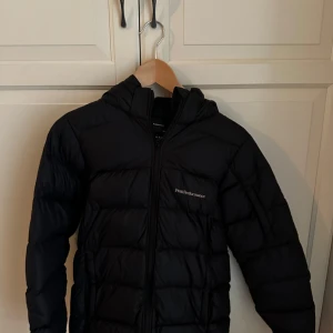 Svart dunjacka från Peak Performance - Säljer en svart dunjacka från Peak Performance storlek 160 men funkar till XS på Dam och sitter bra. 