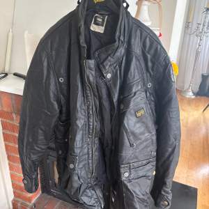 Säljer en svart jacka från G-Star RAW med flera fickor och detaljer som dragkedja och knappar. Jackan har hög krage och en cool, lite robust look. Perfekt för dig som gillar streetwear och vill ha något som sticker ut.
