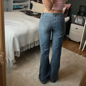 Blå bootcut jeans med låg midja - Säljer ett par blå bootcut jeans med låg midja och dubbla knappar framtill 🩷Dessa är köpta secondhand men var tyvärr för stora på mig! 