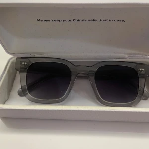 Grå transparenta solglasögon från Chimi - Snygga solglasögon från Chimi med transparent grå båge och fyrkantig form. Glasen är mörka och ger en cool look. Perfekta för dig som vill ha en stilren accessoar med modern känsla. Modell 04