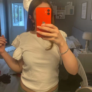 Vit topp med volangärmar - Säljer en söt vit topp med volangärmar och rund halsringning. Fint skick och endast använd en gång💗