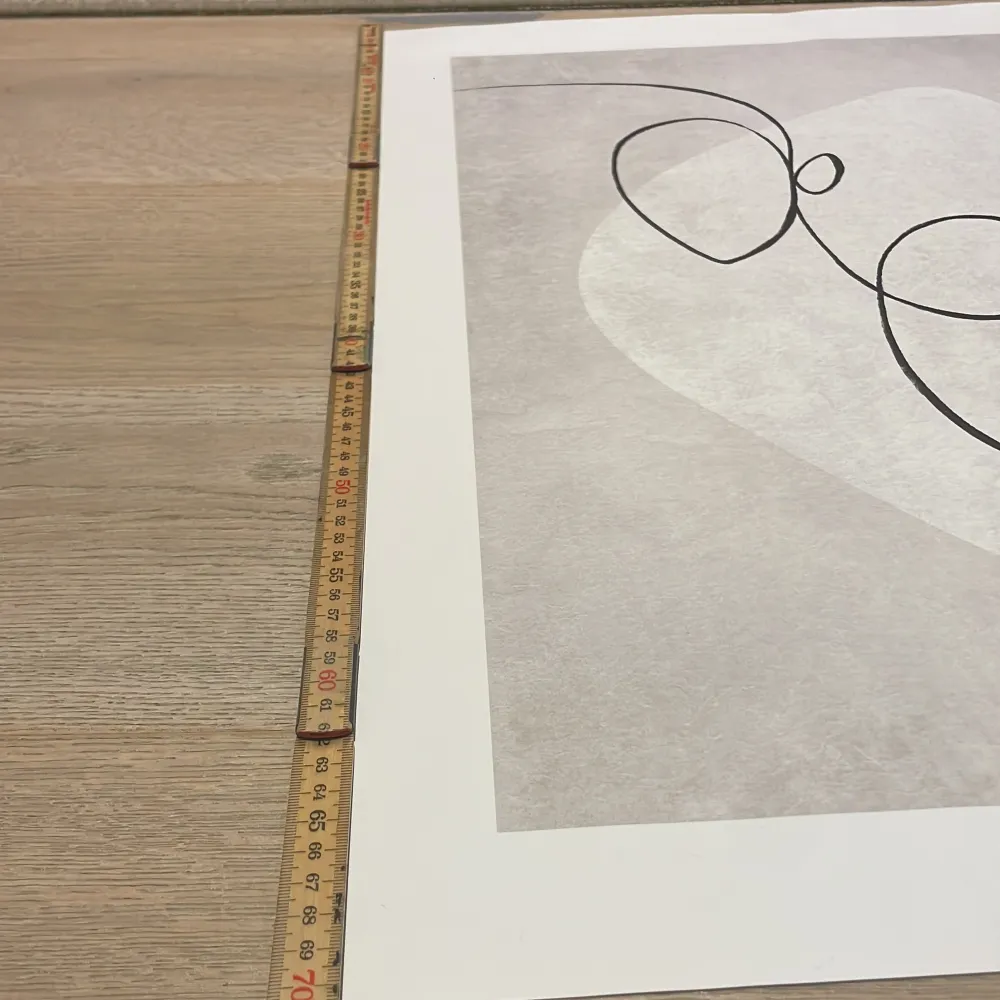 Säljer en stilren poster med abstrakt linjeteckning i svart på en ljusgrå bakgrund. Motivet har mjuka former och minimalistisk design, tryckt på vitt papper. Perfekt för att ge rummet en modern känsla.. Muu.