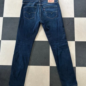 Levi's 502 mörkblå jeans - Mörkblå jeans från Levi's modell 502 med klassisk femficksdesign och raka ben. Snygga kontrastsömmar och läderpatch bak i midjan. 