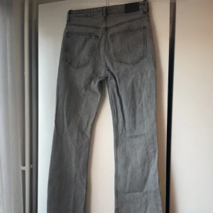 Grå jeansbyxor med raka ben - Säljer ett par klassiska grå jeansbyxor med raka ben och normal passform. Byxorna har fem fickor och synliga sömmar. Perfekta för dig som gillar en enkel och tidlös stil. Har slitningar och är knappt använda💕💕