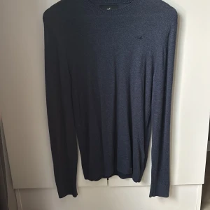 Mörkblå stickad tröja från Hollister - Säljer en stilren mörkblå stickad tröja från Hollister. Tröjan har rund halsringning och långa ärmar, perfekt för vår/sommar. Knappt använd då jag fick den i present av farsan när han var i Kalifornien men var för liten. Storlek: S.