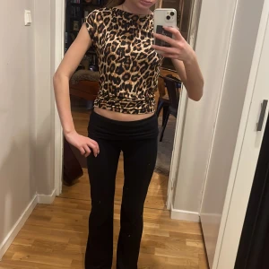 Leopardmönstrad topp med kort ärm - Säljer en snygg leopardmönstrad topp med korta ärmar och rund halsringning. Toppen är figurnära och har ett stretchigt material som sitter skönt på kroppen. Perfekt för dig som vill sticka ut med ett djurmönster!