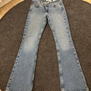 Blå bootcut jeans från Junkyard - Säljer ett par klassiska blå bootcut jeans från Junkyard. Jeansen har fem fickor, ljus tvätt och snygga kontrastsömmar. Perfekta för dig som gillar en retroinspirerad look med utsvängda ben. Lowwaist!! 🥰