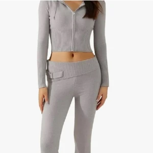 Grå stickade byxor med ribbad midja och bälte - Snygga grå stickade byxor med bred ribbad hög midja och dekorativt bälte med metallspänne. Byxorna har en rak passform med bootcut och är från Novaroni. För tillfället säljer jag endast byxorna men hör av er om ni är intresserade av köpa toppen/ hela setet.