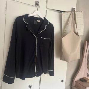 Pyamas!❤️ - Säljer en mörkblå pyjamasskjorta från H&M med vita kontrastkanter och bröstficka. Skjortan har långa ärmar och knäppning framtill. Jätte fin och i bra skick! Skriv vid intresse eller funderingar!🙏