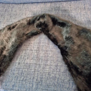 Mörkbrun pälsimitation halsduk - Säljer en mjuk och lyxig halsduk i svart pälsimitation med slät insida i svart tyg. Perfekt accessoar för att hålla värmen och ge en elegant touch till din outfit.