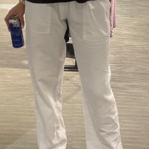 Vita vida byxor med fickor fram - Säljer ett par vita byxor med raka, vida ben och stora fickor framtill. Byxorna har låg midja och är perfekta för en avslappnad men snygg stil. Passar till både sneakers och klackar.