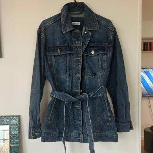 Mörkblå jeansjacka med bälte från Ellos - Säljer en snygg mörkblå jeansjacka med bälte i midjan. 