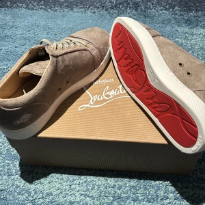 Nya loubs - Säljer ett par exklusiva grå sneakers från Christian Louboutin med klassisk röd sula. Skorna har snörning, rund tå och är tillverkade i mocka. Perfekta för dig som vill ha en stilren och lyxig look. Kontakta via köp/ pris kan diskuteras