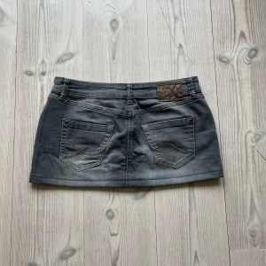 Grå lågmidjad jeanskjol  - Lågmidjad jeanskjol från Mexx i fint skick. Kan inte hitta storlek men skulle säga S/M. Tvärs över midjan är det 39 cm och den är ca 27 cm lång. Använd gärna köp nu!