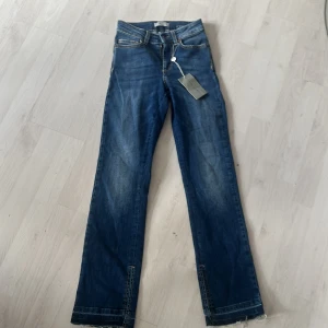 Blå jeansbyxor från Hunkydory  - Snygga blå jeansbyxor från Hunkydory i modellen Earl Denim med mid indigo wash. Klassisk femficksdesign och raka ben. Perfekta för dig som gillar en tidlös jeansstil. Säljer för dem är lite korta för mig är 1,64