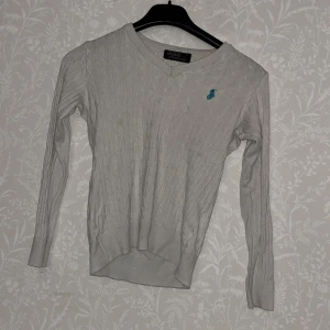 Vit ribbad tröja från Polo Ralph Lauren - Säljer en vit ribbad tröja från Polo Ralph Lauren med v-ringning och lång ärm. Säljer pga den är för liten för mig, jag har köpt den från en annan person som säljer men jag tyckte inte om den. Säljer för 100:- den kan ha några små fläckar men man tänker ej på det.