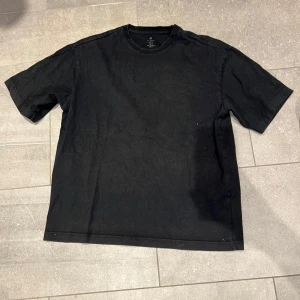Svart t-shirt - En basic svart t-shirt med realxed passform och lite längre ärmar. Perfekt till jeans eller shorts för en enkel och stilren look. Gjord i tjockt och tåligtmaterial som känns skönt mot huden.