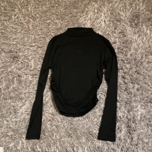 Svart polotröja med långa ärmar - Säljer en svart polotröja med långa ärmar. Tröjan är enkel och stilren, perfekt att matcha med olika outfits. Materialet känns mjukt och stretchigt, vilket gör den bekväm att bära.