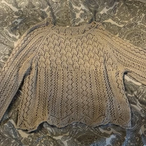 Beige stickad tröja från ONLY - Säljer en beige stickad tröja från ONLY i storlek XS. Tröjan har ett luftigt, virkat mönster och långa ärmar. Perfekt för lager-på-lager och ger en bohemisk känsla till outfiten. Tröjan har inte fulllängds ärmar, men inte helt trekvart heller.