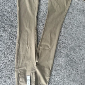 Beiga kostymbyxor - Oanvända kostymbyxor i storlek 34. Utsvängda.