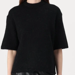 Svart stickad tröja med halvärm - En enkel och stilren svart stickad tröja med rak passform och halvärm. Perfekt att styla med både jeans och kjol för en clean look.