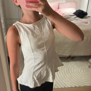 Vit ärmlös topp från MNG - Säljer en stilren vit ärmlös topp från MNG. Toppen har en lätt utsvängd passform och markerade sömmar framtill som ger en snygg siluett. Perfekt att matcha med jeans eller kjol för en fräsch look.