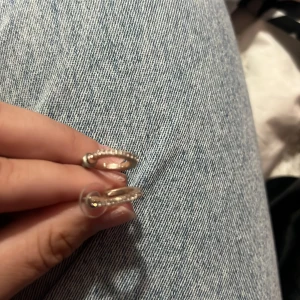 Glittriga silverörhängen i hoops - Säljer ett par snygga hoops i silverfärg med glittriga stenar på framsidan. Örhängena är små och runda, perfekta för att ge lite extra bling till din look. Passar dig som gillar stilrena smycken med en touch av glitter.