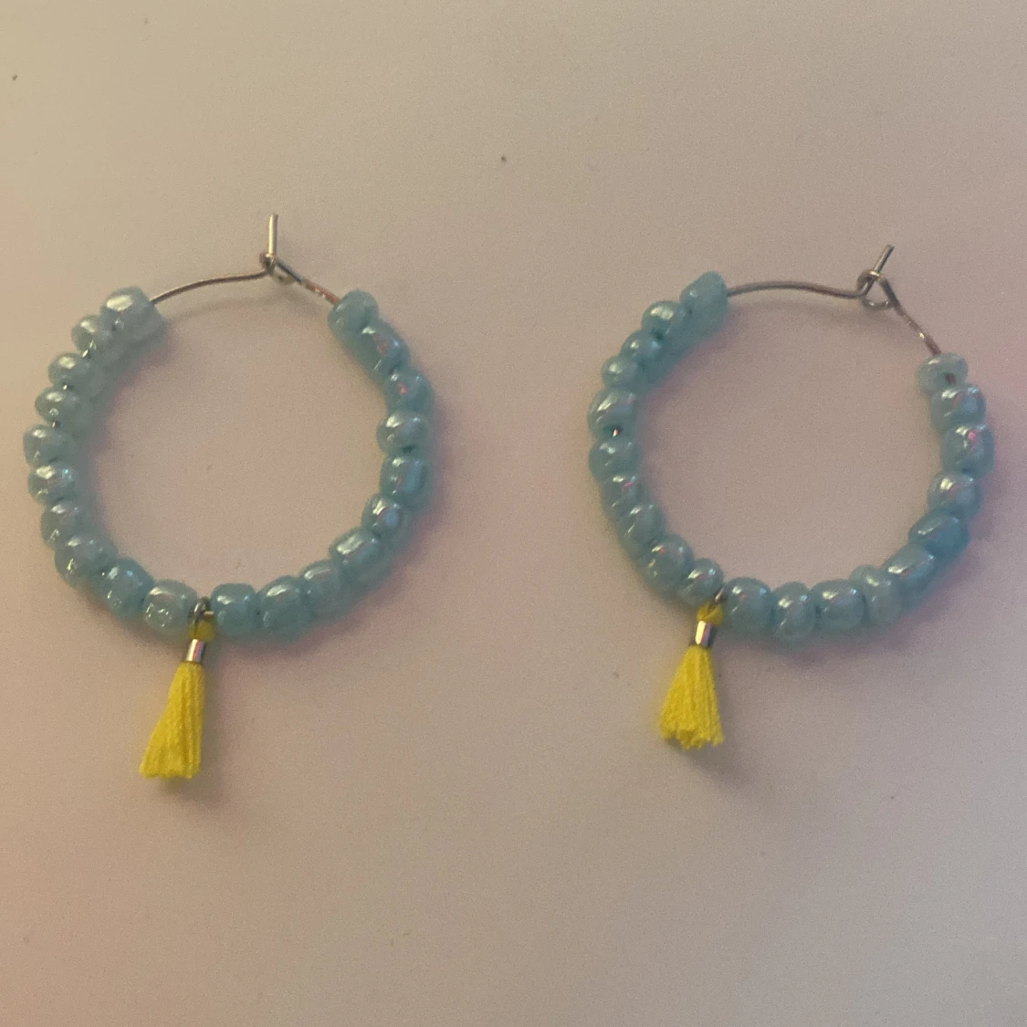 Blå pärlörhängen med gul tofs
