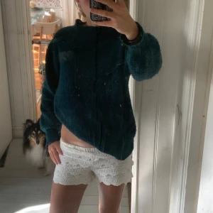 Mörkgrön stickad tröja från Canda - Mysig mörkgrön stickad tröja från Canda med rund hals och ribbade muddar. Tröjan har en loose passform och är perfekt för kyliga dagar. Materialet är mjukt och fluffigt, vilket gör den extra skön att bära. Den är nopprig. 