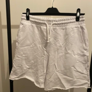 Vita shorts med snörning från H&M - Vita shorts från H&M med elastisk midja och snörning framtill. Tillverkade i mjuk bomull med rå kant nedtill för en chill vibe. Har sidofickor och är perfekta för varma dagar. Materialet består av 22% återvunnen bomull.