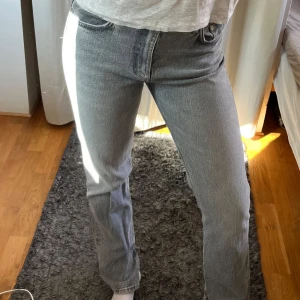 Grå raka jeans med slits nertill - Snygga grå jeans med rak passform och hög midja. Jeansen har klassisk femficksdesign och en cool slits nertill på benen. 
