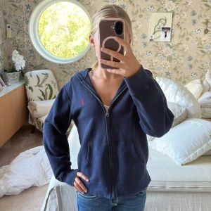 Mörkblå hoodie från Polo Ralph Lauren - Säljer en mörkblå hoodie från Polo Ralph Lauren med dragkedja och huva. Har använt kanske 3 gånger typ och säljer då den inte används. Köpte för 1000 kr❤️