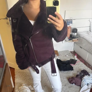 Vinröd shearlingjacka - Säljer en snygg mörklila pälsjacka med pälskrage och spännen i midjan. Slutar precis under mitten av rumpan på mig som är 152. 