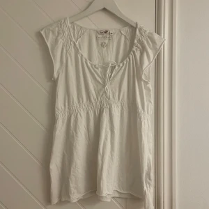 Vit blus med knyt från EastWest - Supersöt vit blus från EastWest med knyt framtill. Köpt secondhand och jag själv har aldrig användning. Den är i mycket bra skick med inga tecken på användning. Är i storlek M.