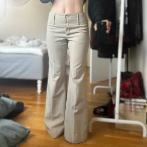 Beiga vida kostymbyxor  - Säljer dessa snygga vida/bootcut kostymbyxor då de är lite för långa på mig (står på tå på bilden då jag är 158cm) Byxorna har två knappar framtill och pressveck. Perfekta för en clean och stilren look. Skriv för mått/mer info❤️