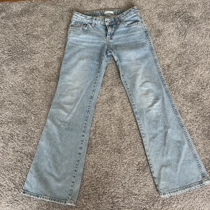 Bootcut ljusblå jeans från Gina  - Ljusblå lågmidjade jeans från Gina med fickor med knappar där bak. Midjemått: 38cm rakt över. Innerbenslängd: 78 cm