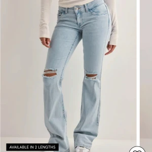 Bootcut ljusblå jeans nelly - Snygga ljusblå bootcut jeans med slitna hål på knäna och coolt rosa zigzag-broderi på bakfickorna. Jeansen har klassisk femficksdesign, normal passform och är tillverkade i mjukt denim. Perfekta för dig som gillar en avslappnad och trendig stil.