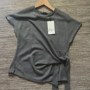 Grå knyt-topp från Zara - Säljer en omlott top då den inte används!! Endast prövad prislapp kvar , helt som ny💕 Storlek M men passar även S