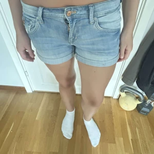 Ljusblå jeansshorts från hm - Snygga ljusblå jeansshorts från Denim med klassisk femficksdesign, knapp och dragkedja framtill samt detaljerade bakfickor med knapp. Shortsen har låg midja och är gjorda i mjukt jeansmaterial, perfekta för varma dagar.