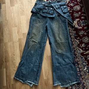 Baggy jeans med avtagbar kjol - Trendiga jeans från Ranger Cartel med avtagbar kjol. Aldrig använda. Lappen sitter kvar samt originella påsen medkommer. Skriv för fler bilder. Att beställa nya kostar mycket pga tullar och fraktavgift från USA därav det dyra priset.