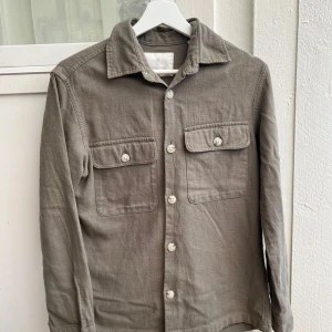 Ljusgrön overshirt från Jack & Jones XS - Snygg overshirt från Jack & Jones i bomull. Modellen har klassisk krage, två stora bröstfickor med knappar och långa ärmar. Perfekt att slänga över en t-shirt för en chill look.