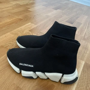 Balenciaga svarta sock sneakers - Svarta Balenciaga sneakers med stickad ovandel som sitter som en strumpa runt foten. Vit chunky sula med coola detaljer och Balenciaga-logga på sidan. Riktigt futuristisk vibe och perfekt för dig som gillar streetstyle.