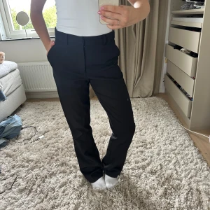 Kostymbyxa - Svarta kostymbyxor med hög midja. Fickor fram och bak. 