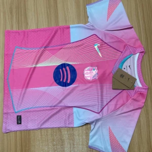 Nike Barcelona rosa fotbollströja S - Snygg Barcelona fotbollströja från Nike i Dri-FIT-material. Tröjan är rosa med ljusblå och vita detaljer, har korta ärmar och ett futuristiskt mönster med tunna linjer. Klubblogga och Nike-logga på bröstet samt sponsortryck i blått framtill.