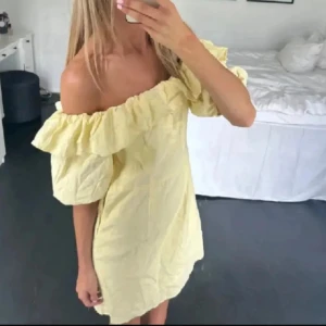 Trendig klänning - Söt ljusgul kortklänning med offshoulder och volangdetaljer runt axlarna. Klänningen har puffiga korta ärmar och en luftig passform, perfekt för varma dagar. Materialet känns lätt och somrigt. Storlek M men passar mig som är xs/s