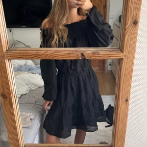 Svart offshoulder klänning H&M XS - Supersnygg svart kortklänning från H&M i storlek XS. Klänningen har offshoulder-design med smock upptill och långa puffiga armar. Använd 1 gång. Klicka gärna på ”köp nu”!🧸