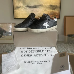 Golden Goose Superstar Sneaker - Säljer ett par otroligt snygga Golden Goose superstar i mycket fint skick. Skorna är som nya förutom lite slitage på sulan/innersulan, se bild 3,4. Box, Dustbag, Äkthetscertifikat och kvitto tillkommer. (OBS! Skoblock följer inte med) Köpta för 3,899kr på Second place så självklart är skorna äkta ,men har du några frågor så skriv privat!