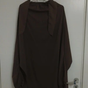 Brun Khimar set  - Säljer en brun Khimar med lång överdel och en kjol under med knytband vid halsen och långa ärmar med lätt puff vid mudden. Khimaren har en loose passform och materialet känns mjukt och skönt mot huden, är gjord av högkvalite. 