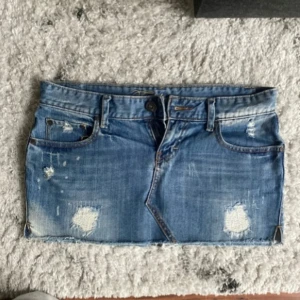 Blå jeanskjol med slitningar - Snygg low waist mini jeanskjol i strl 38, midja:42. Kommer fler unika jeansshorts o kjolar så följ!!