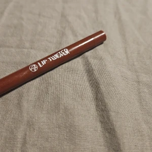 W7 Lip Twister läppenna Shiraz - Läppennan Lip Twister från W7 i färgen Shiraz är en snygg brunröd nyans. Pennan har en klassisk smal form och är perfekt för att definiera läpparna eller skapa en fylligare look. Enkel att applicera och passar till många olika läppstift.